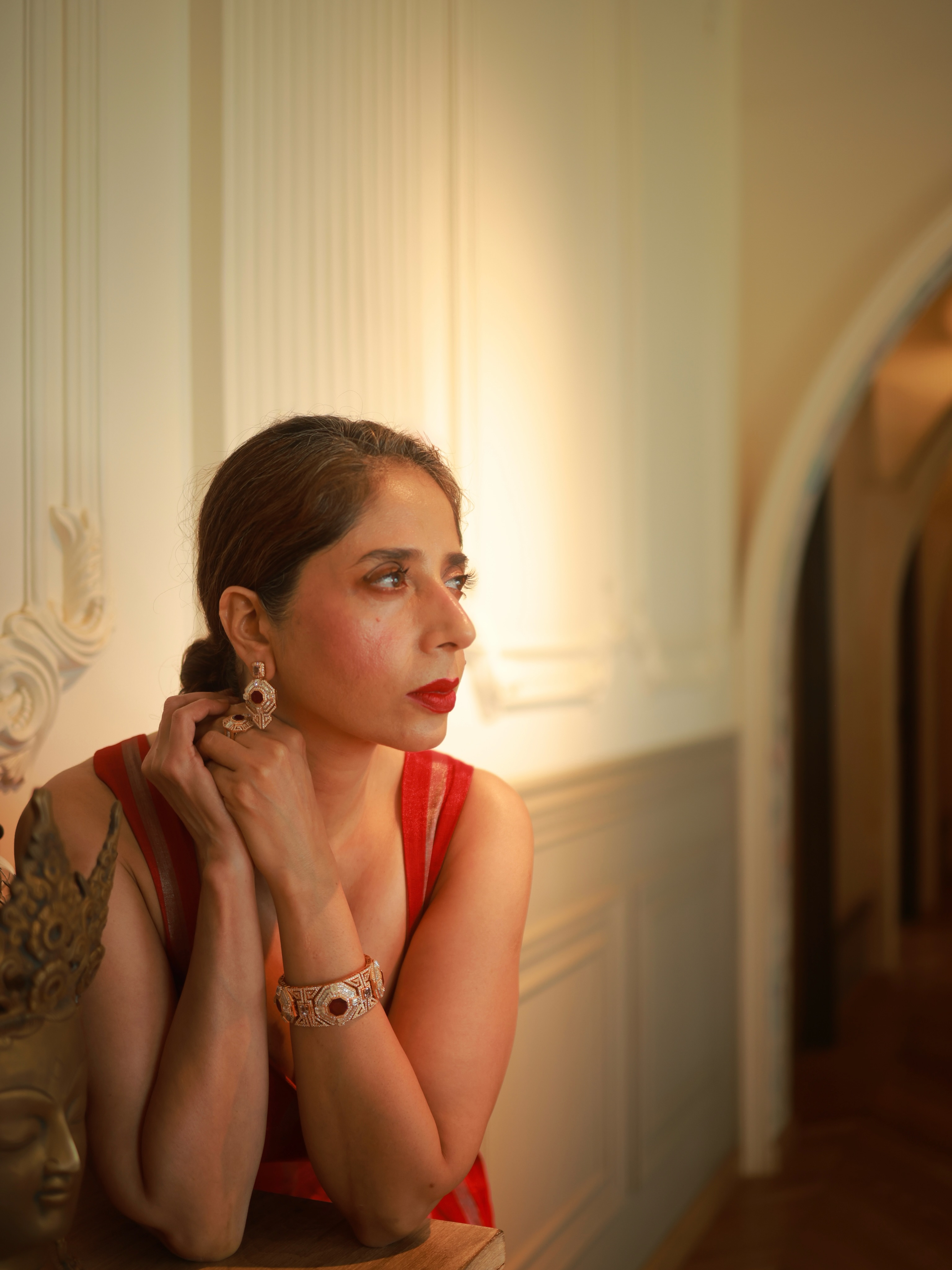 Aiana in a red saree with statement jewellery in warm golden light